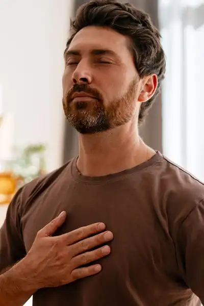 Man in brown tee in his home breathing