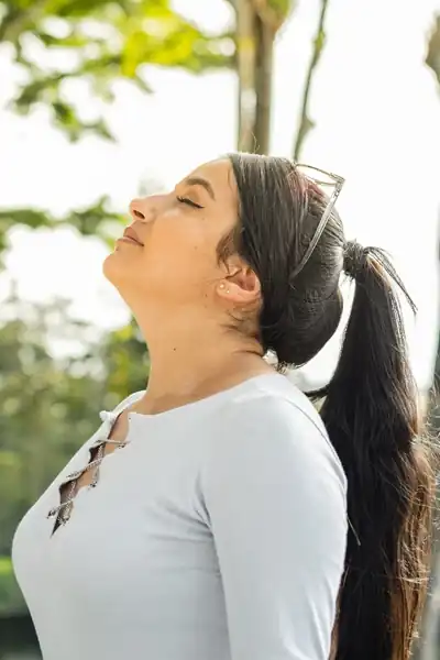 Woman in a park taking a big breath of fresh air