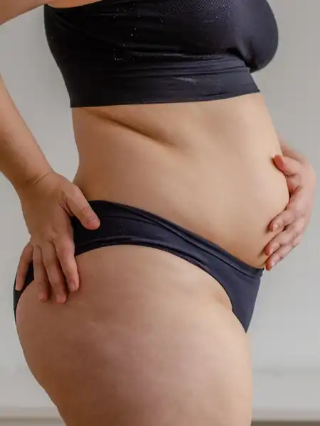 Woman in black underwear with hand on hips and stomach